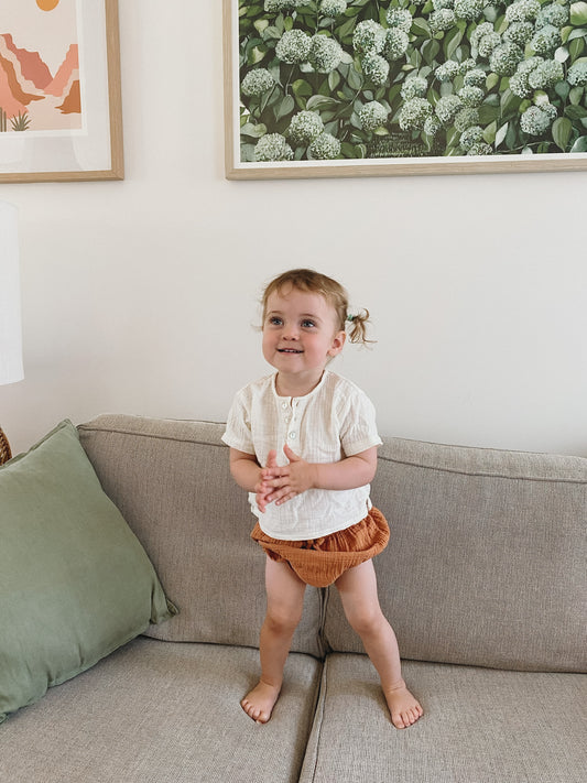 Toddler wearing organic cotton muslin shirt and shorts for baby lounging and play